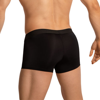 The image features a confident person from the back wearing Edipous Mens Boxer Trunks in black with modern swagger. With legs slightly apart and a partially visible left arm, their light skin tone contrasts against the solid black waistband of these Edipous trunks.