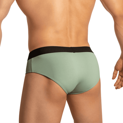 A person models Edipous Briefs for Men Open Front, featuring light green fabric and a black waistband, as seen from behind. The plain background accentuates the alluring fit and style of this underwear by Edipous.
