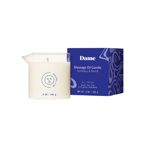 Dame Massage Oil Candle in Melt Together, a white wax-filled glass jar with a pour spout, beside its blue box