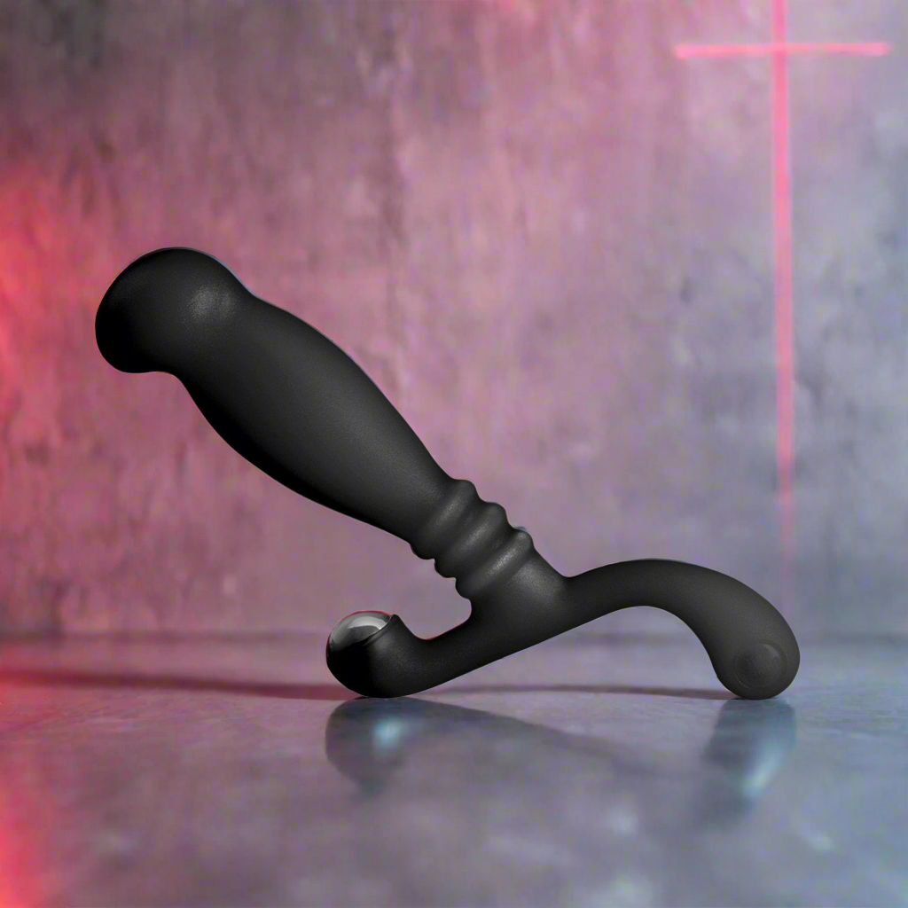 A Nexus Glide Prostate Massager by Nexus, featuring a black ergonomic S-shaped design with a curved handle, rests on a reflective surface. The background displays a textured wall with a subtle red cross projection, highlighting its perineum stimulation allure.
