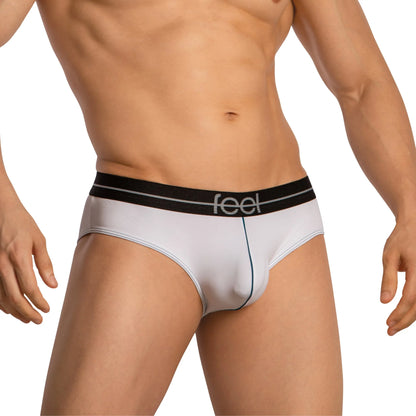 A person stands against a plain backdrop wearing Feel Thongs for Men. These white briefs feature a black waistband with Feel printed on it and offer minimal coverage, hinting at a luxurious fabric blend that promises comfort and style.