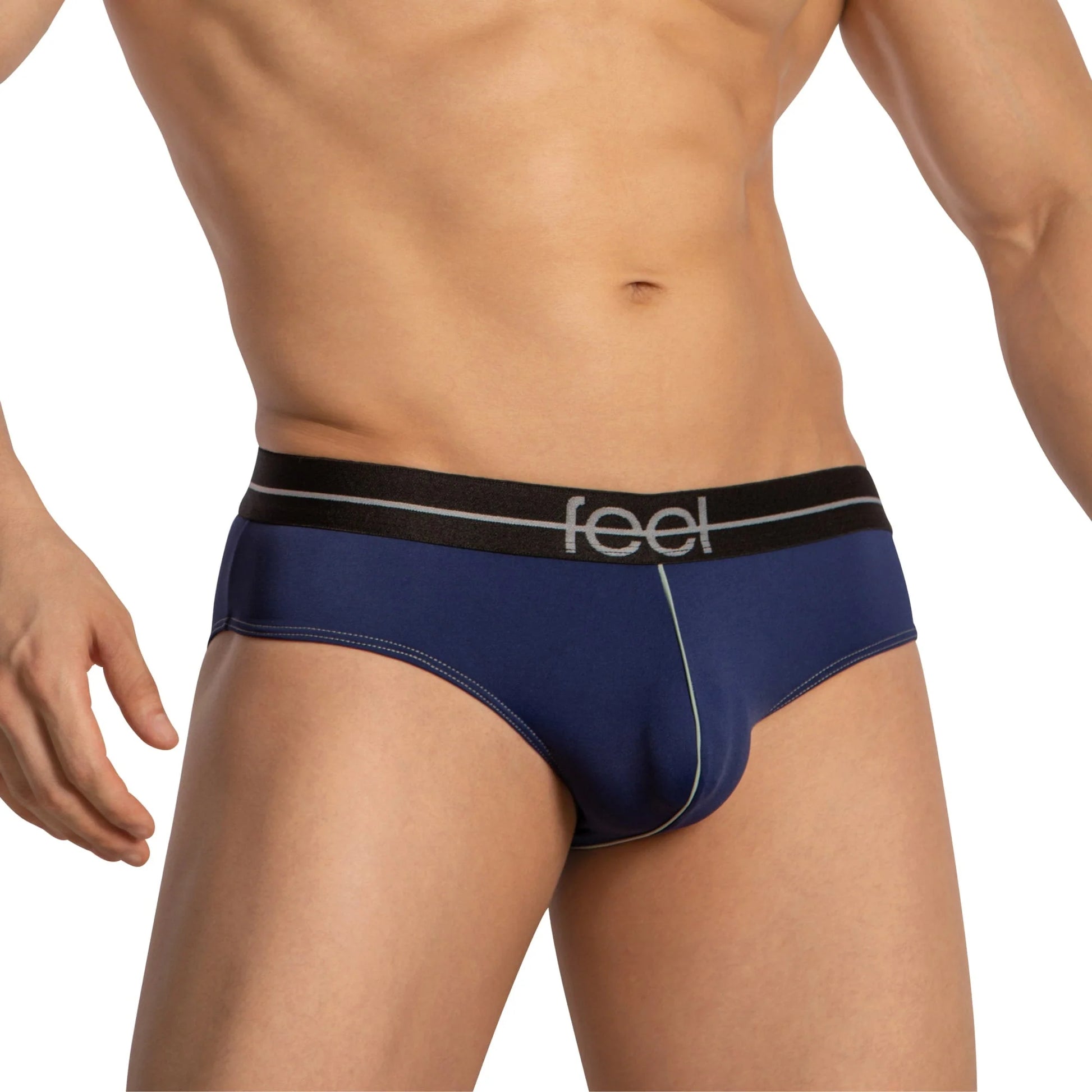 A person wears Feel Thongs for Men, featuring blue fabric with minimal coverage and a black waistband displaying Feel. Light green stitching highlights the luxurious blend. The background is white.