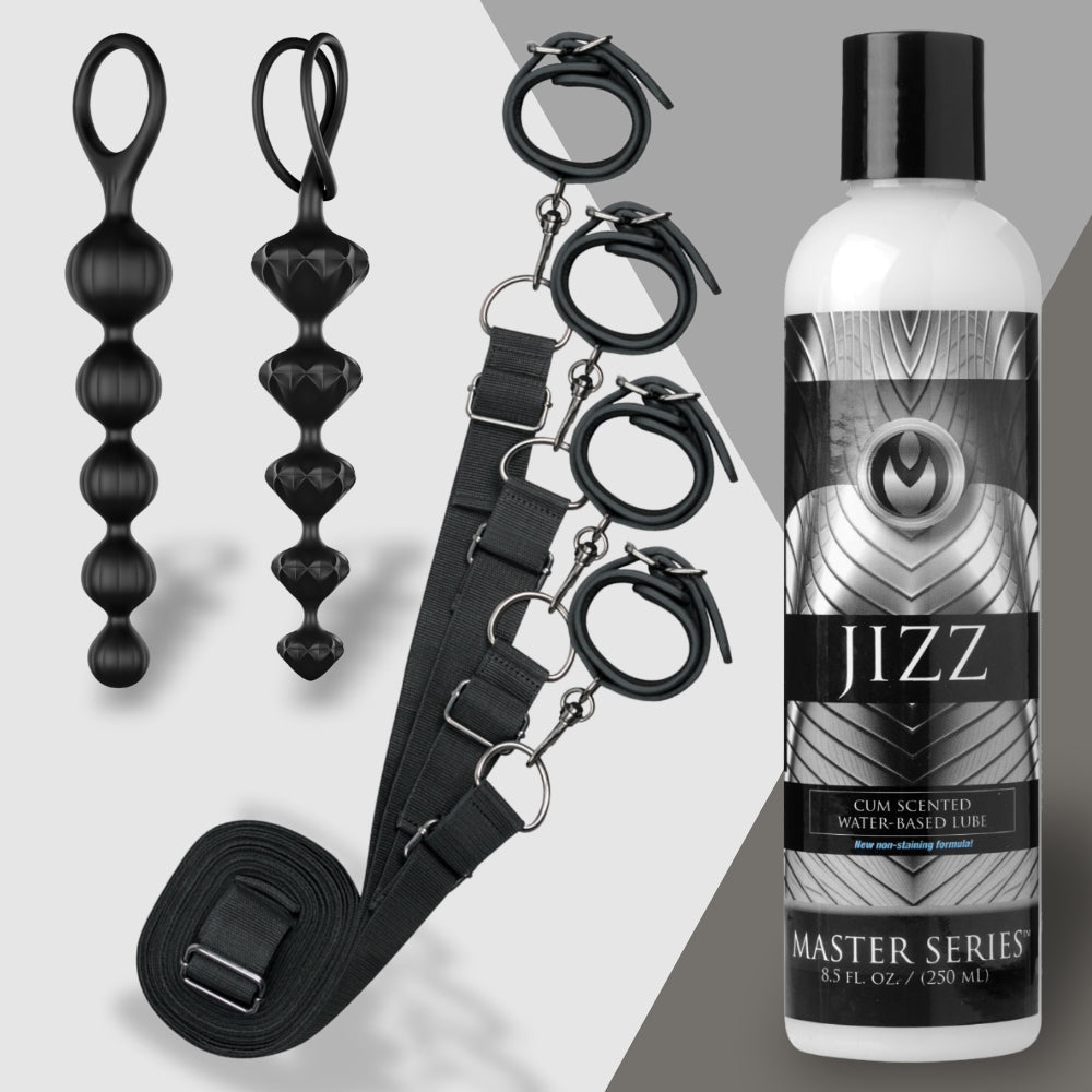 The image showcases Rough and Ready by Adams Toy Box, featuring black restraint cuffs linked by a strap, two sleek black bead toys, and a bottle of water-based lubricant labeled Master Series against a minimalist gray two-tone background.