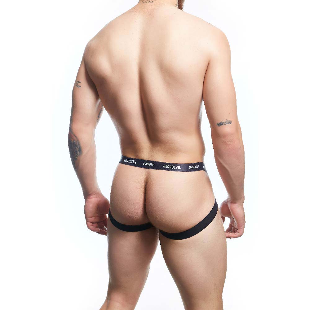 A tattooed person with a short haircut poses from the back in a Good Devil Sexy Men Jockstrap made of Premium Fabric Blend, set against a white background. The waistband reads Good Devil.