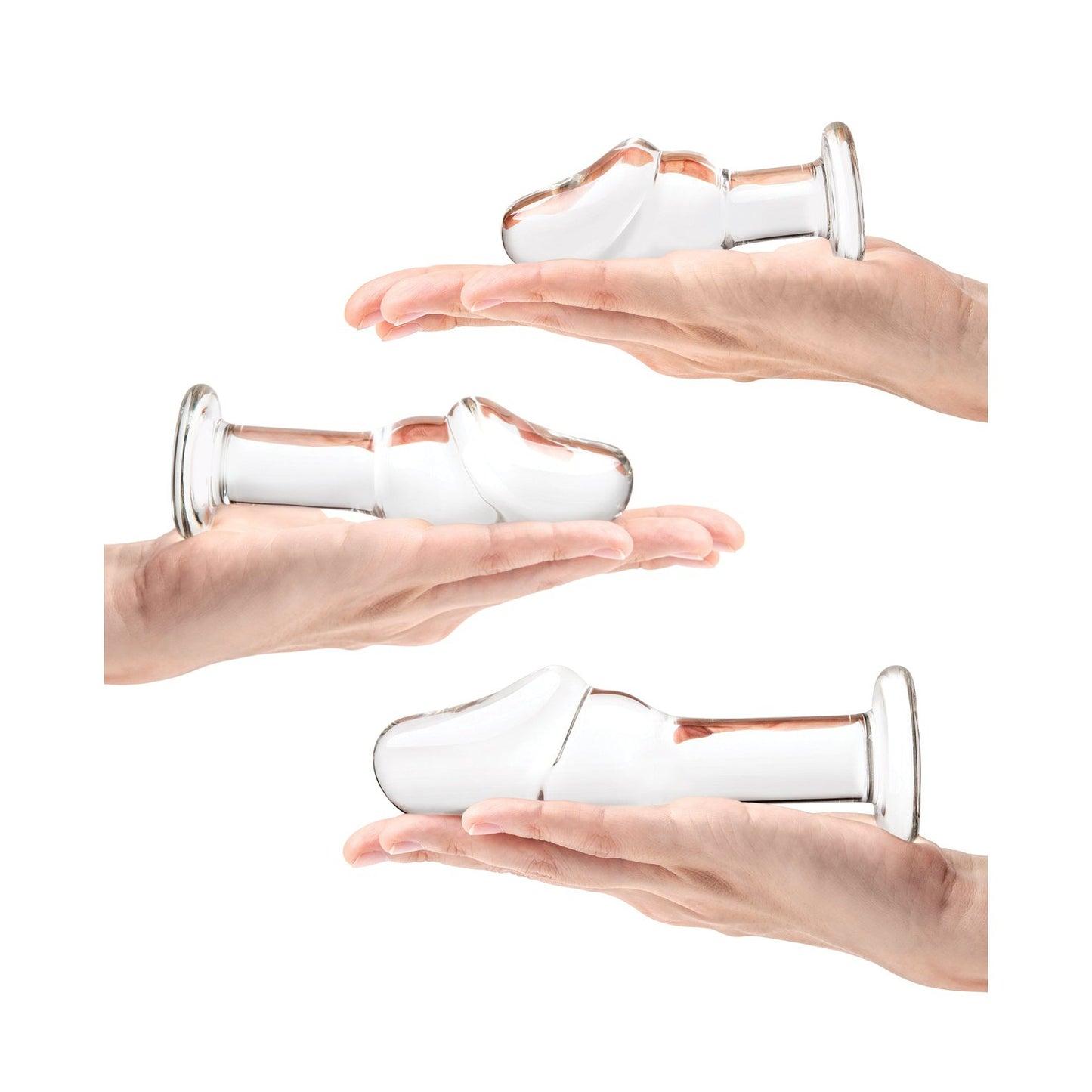 Against a plain white background, three hands hold unique items from the Glas Helmet Head Anal Training Kit by Gläs—each glass piece with rounded ends and flat bases, subtly suggesting temperature play in the scenes serene simplicity.
