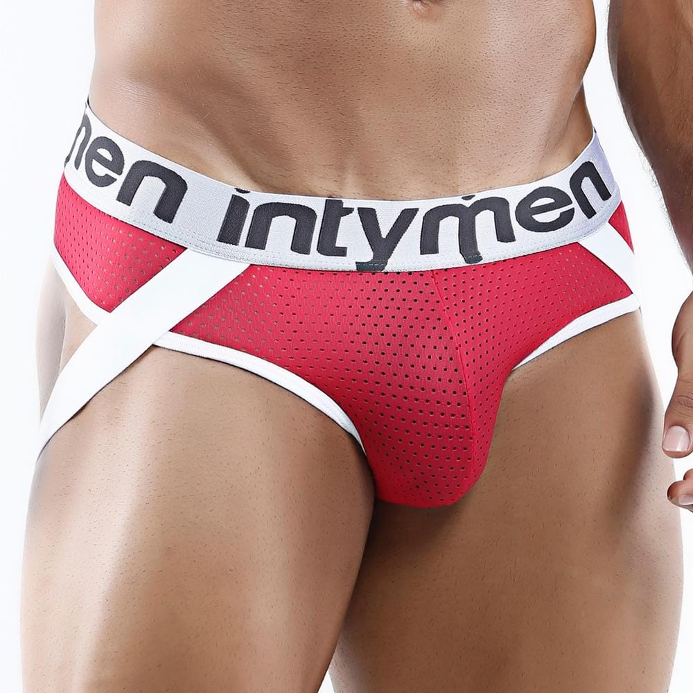 A person is wearing the Intymen Game Jockstrap, showcasing red and white athletic underwear with Intymen on the waistband. This erotic design includes a perforated mesh fabric for breathability.