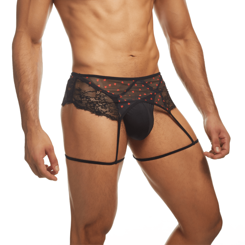 A person wears Secret Males romantic Flower Laced Peek-a-boo Lingerie with hearts, featuring black lace, red heart patterns, a garter belt, and straps. Black underwear completes the Valentines Day ensemble against a simple white backdrop.