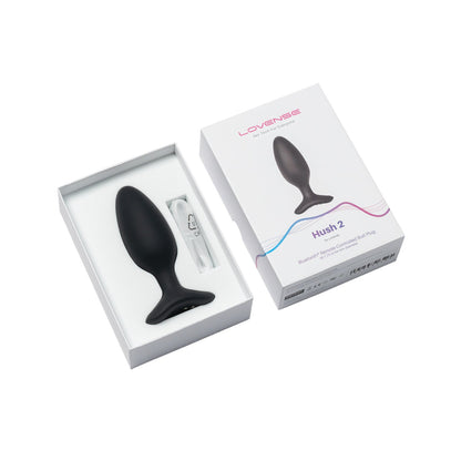 A sleek, black teardrop-shaped device elegantly rests beside its packaging, revealing the Lovense Hush 2 Butt Plug, a Bluetooth remote-controlled vibrator made of 100% silicone, designed to be a silent partner for intimate moments.