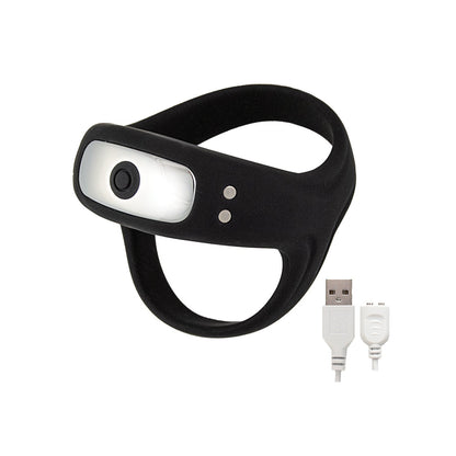 The Cockpower Scrotum and Cock Ring by Nasstoys is a black silicone looped wearable, featuring a central light or sensor, and comes with a white USB charging cable.