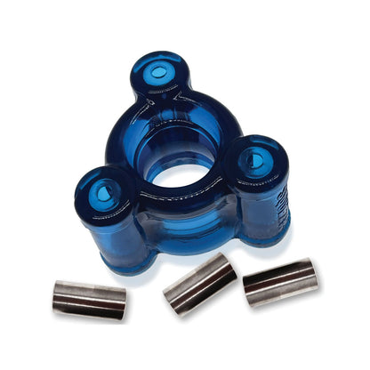 The Oxballs Heavy Squeeze Ballstretcher, a blue transparent geometric plastic piece with three cylindrical extensions around a central hole, features a perfectly balanced design. Below it, three shiny stainless steel weights rest on a white surface.
