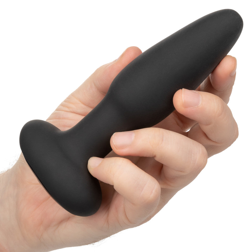A hand holds a black silicone plug with a flared base and smooth, tapered design. This sleek device, the Bionic Pressure Rimming Probe by California Exotic Novelties, offers thrilling vibrations when activated.