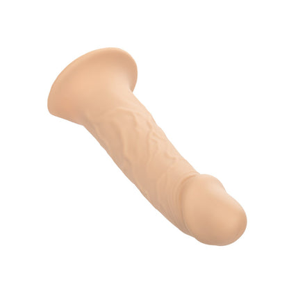 The Performance Maxx Life-Like Penis Extension With Harness by California Exotic Novelties is a beige silicone dildo with a realistic design, featuring textured veins and a flared base, angled to the side on a white background.