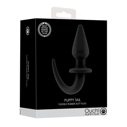The image shows the packaging for the Shots Ouch Puppy Play Tail Butt Plug by Shots Ouch. The chic black-and-white box highlights its waterproof design for easy insertion, and a Best British Brand badge on the top left corner adds prestige.