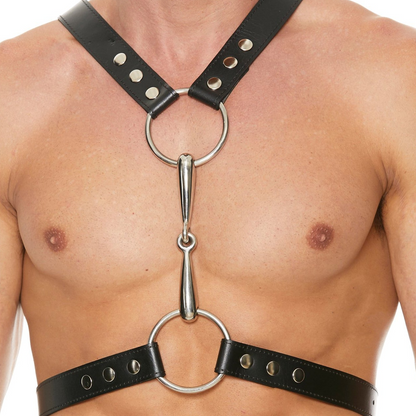 An individual dons the Shots Ouch Uomo Mens Harness featuring a black leather design with metal rings and studs. This adjustable harness showcases two main rings linked by a central metal piece and chest straps, epitomizing bold bondage fashion.