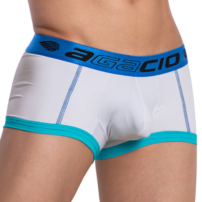 A person wears Agacio Stretch Boxer Trunk in white and turquoise, featuring a blue waistband with Agacio branding. The double-stitched pouch enhances comfort, centering attention on the lower torso and underwear with no visible background.