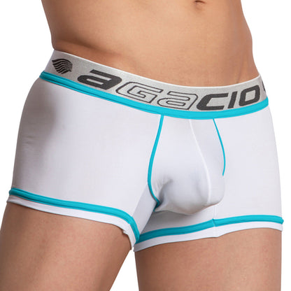 A person models the Agacio Bi-color Boxer Trunk with a sleek design in white and turquoise, featuring an elastic waistband with black lettering and a small emblem on the left side. The focus is on the midsection and legs, highlighting the smooth stitching.