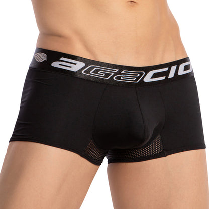 A person in Agacios black mens underwear with supportive fit and branded waistband showcasing Agacio in white. The breathable boxer trunk has mesh side detailing, with the image highlighting the midsection, excluding face and legs.