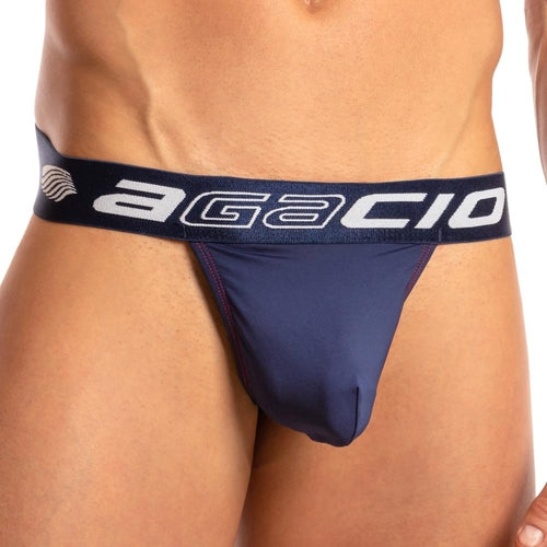 A person is wearing an Agacio Chic Thong in navy blue, highlighted by a black waistband with the brand name in bold white font. It features an enhancing pouch and is set against a plain white backdrop that perfectly accentuates the mens thong.