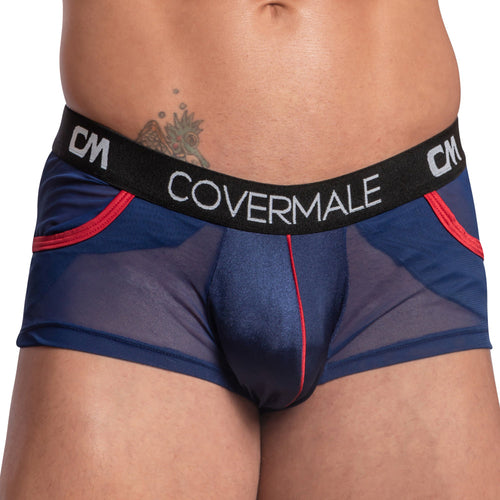 A person wears the Cover Male Center Piping Boxer Trunk, featuring a blue color with red trim and a Cover Male waistband. The sides are partially see-through for added allure, while center piping provides structure. A small tattoo is visible on the lower abdomen.