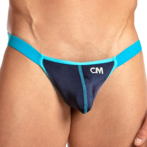 Modeling a sleek Cover Male Striker Thong, this sporty piece features a contoured pouch with CM initials. The vibrant blue and turquoise stand out against a beige background, highlighting its refined design.