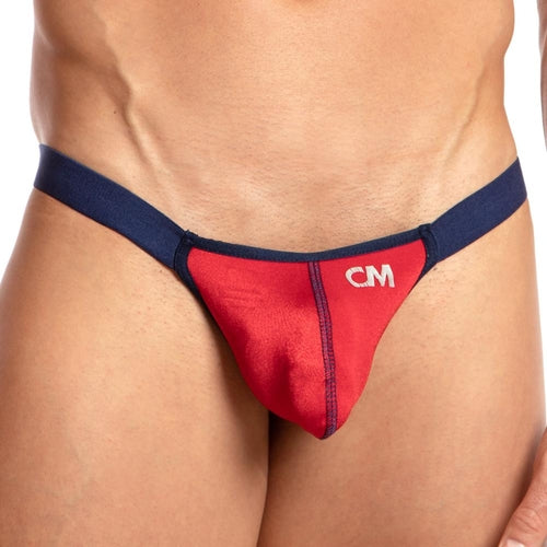 A person models a red and navy blue Cover Male Striker Thong, featuring CM initials on the front. The image emphasizes its sleek, sporty design and contoured pouch for an ideal fit.