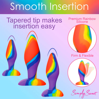 The Curve Toys Simply Sweet Rainbow Silicone Butt Plug Set by Curve Novelties features three colorful, body-safe silicone plugs with tapered tips. Described as firm and flexible, they ensure smooth insertion and are ideal for anal training. The background highlights Smooth Insertion branding.