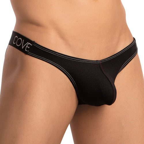 Close-up of a person wearing the Cover Male Cross String Back Jockstrap in black, featuring an alluring strap design, stylish hip band with white stitching, and a COVE branded waistband. The background is plain white.