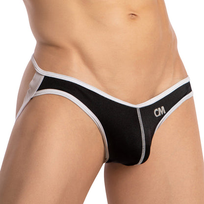 A person is wearing a Cover Male Centerseam Open Back Jockstrap in black and white, featuring CM initials on the side. The image highlights the lower torso and hips, showcasing its breathable fabric for added comfort and style.