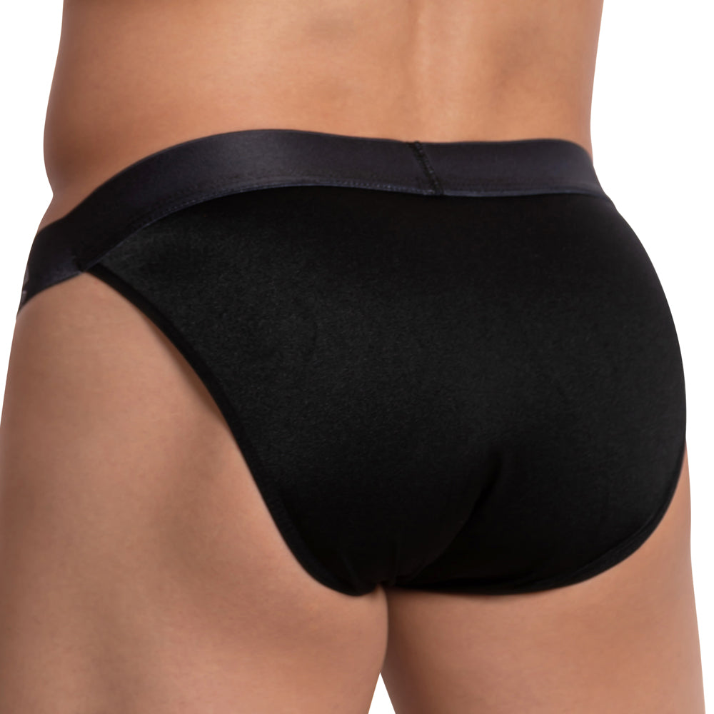 A person is seen from the back wearing Cover Males Color Me Bikini for men. The style includes color-contrast piping on smooth, shiny material, standing out against a plain, light-colored background and highlighting its lightweight fabric.