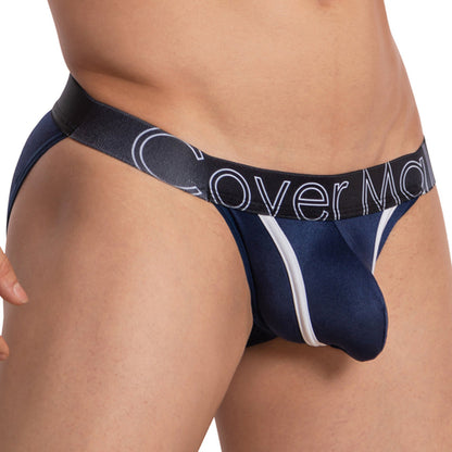 A close-up of someone wearing Cover Males Color Me Bikini in navy blue and black shows color-contrast piping and bold branding on the waistband. The lightweight fabric offers a form-fitting, minimalistic design for comfort and style.