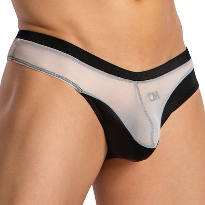 A close-up of a person wearing the Cover Male Almost Naked Thong by Cover Male, in black and white mesh with a CM logo on the front, offers an ultra-comfortable fit that accentuates the hip and upper thigh.