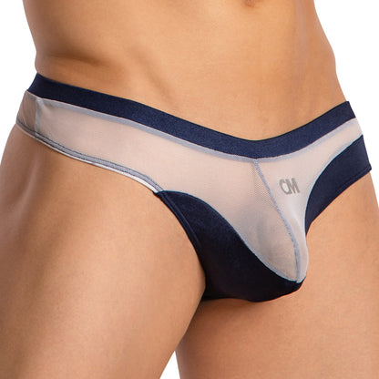 A close-up of a person wearing the Cover Male Almost Naked Thong by Cover Male, featuring an eye-catching navy blue mesh design, a visible waistband, and CM printed on the front left side.