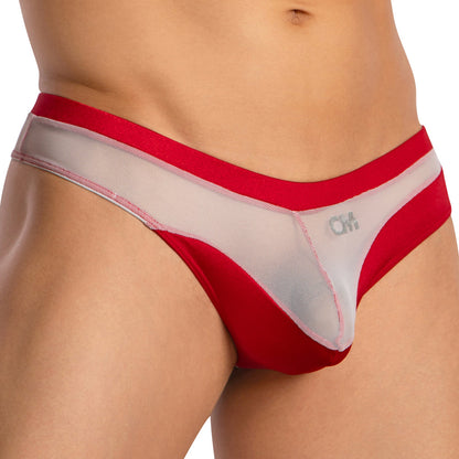 Close-up of a person wearing the Cover Male Almost Naked Thong by Cover Male, featuring an eye-catching red and white mesh design with the brand logo on the white panel. The image shows the torso and upper thighs.