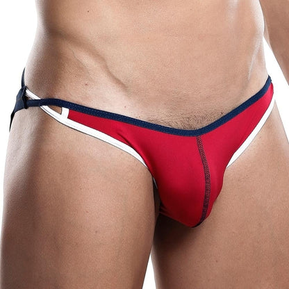 Wearing a Daddy Jockstrap by Daddy in a red and navy blue bikini style with white trim, this sleek piece features tie strings at the sides. The image captures from waist to mid-thigh, showcasing its minimal and enticing design that complements the contoured pouch style.