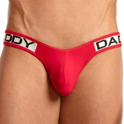 Wearing the Daddy Invisible Jockstrap, a person highlights their red underwear featuring a waistband boldly labeled DADDY, emphasizing the appealing pouch and waist.