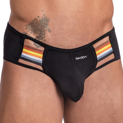A person dons a seductive Daddy Gay Jockstrap, featuring black briefs with mesh side panels adorned with rainbow stripes and DADDY boldly printed on the waistband, complementing their torso tattoo.