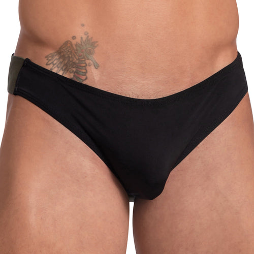 The person is wearing a Daddy Wide Waistband Jockstrap, supporting the midsection and waist. A winged symbol tattoo is visible near the hip against a plain white background.