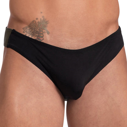 The person is wearing a Daddy Wide Waistband Jockstrap, supporting the midsection and waist. A winged symbol tattoo is visible near the hip against a plain white background.