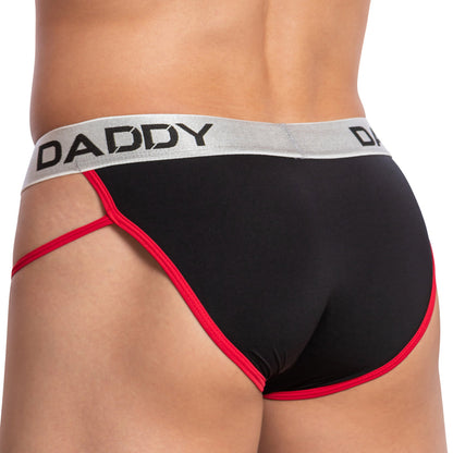 A person wearing a Daddy Alluring Brief, featuring an enhancing pouch with black material, red trim, and a gray waistband displaying DADDY in bold black letters. The side angle highlights the sleek design on the lower back and underwear.