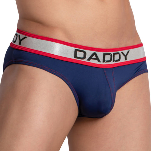 Close-up image of a person wearing Daddys navy blue Dazzler Briefs with a red and silver waistband featuring DADDY. These briefs offer a body-enhancing fit and are made from shiny, stretchy fabric for comfort and style.