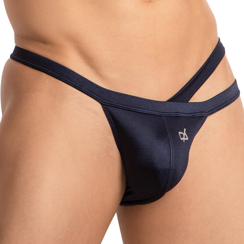 A close-up shows a person wearing the Daniel Alexander Dual Strapped Bikini in dark blue, featuring a minimal strap design and high-quality fabric. The waistband has a small white embroidered logo on the left, contrasting with light skin and set against a plain white background.