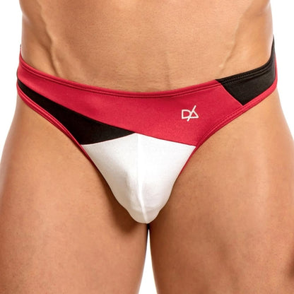 The image features someone wearing the Daniel Alexander Slash Thong, characterized by a color-block design in red, black, and white with an abstract logo on the waistband and an enhancing pouch for added comfort. The focus is on the garments sleek design.
