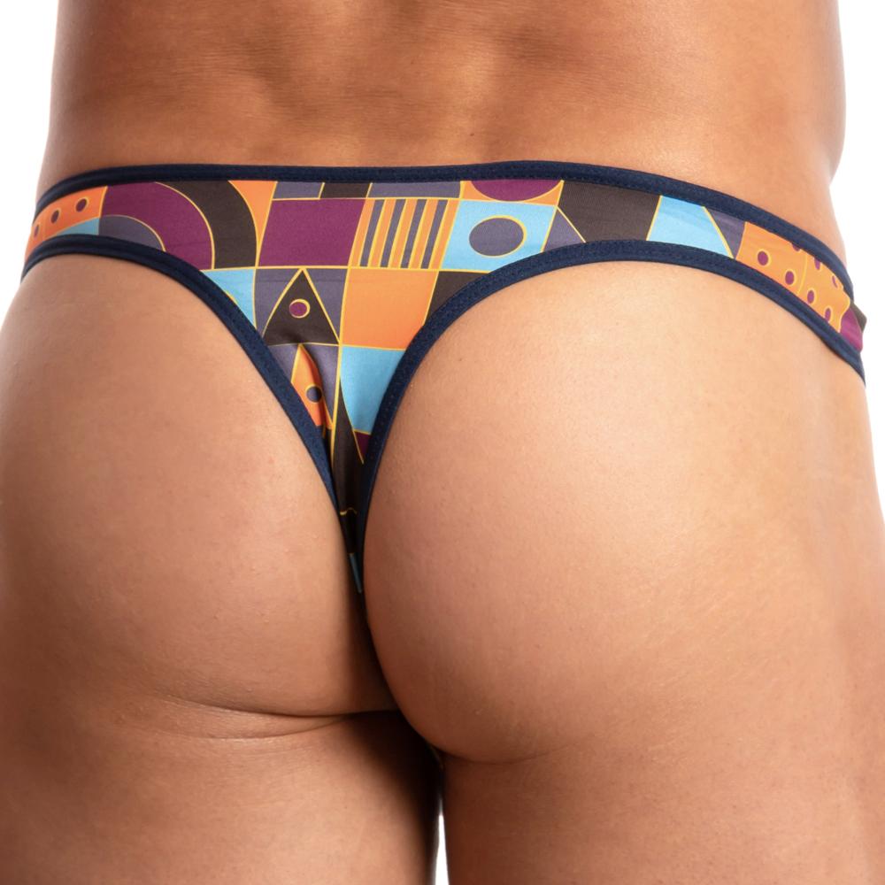 A person models the Daniel Alexander Limited Ass Kini Thong, showcasing a sleek, stretchy waistband and vibrant geometric patterns of circles and triangles in orange, blue, and purple from a rear view.