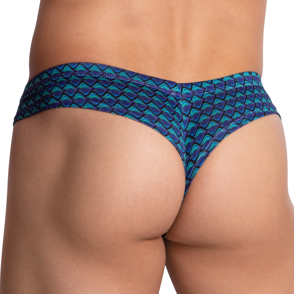 A close-up of a person wearing the Daniel Alexander Glare Thong in a colorful blue and green geometric pattern. Made from a breathable polyamide-spandex blend, it emphasizes fit and texture while highlighting the V-shaped pouch for added comfort.