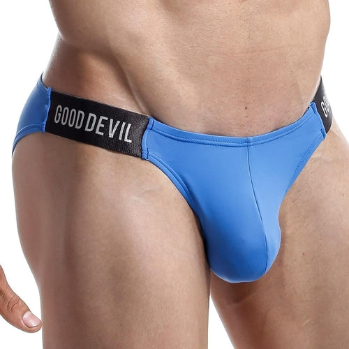 A person wearing the Good Devil Micro Bikini, featuring a low-waist design with a black waistband branded GOOD DEVIL in white. The form-fitting mens designer briefs add a sexy touch to mens swimwear, and the persons hand is partially visible.