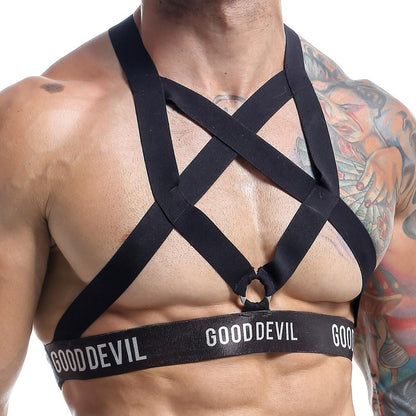 A man showcases his chest-baring glory in a black harness emblazoned with Good Devil. The Good Devil Accessories criss-cross design complements his colorful tattoos, creating a striking look.