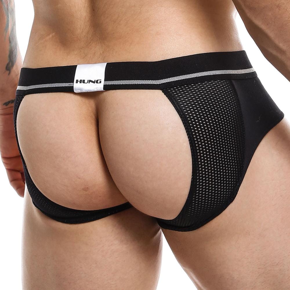 A person wears the Hung Jockstrap by Hung, featuring a black design with a breathable mesh pouch and a white HUNG label on the waistband. The image artistically emphasizes the lower back and glutes.