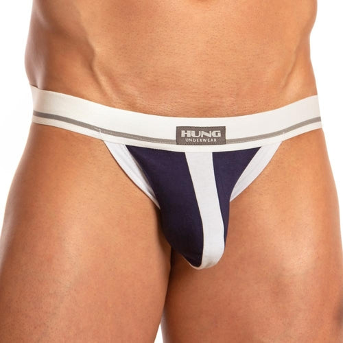 A model showcases the Hung Dong Jocks navy and white briefs style with supportive straps. It features a bold thick white waistband with HUNG Underwear and a vertical white stripe, all captured in this lower torso image.