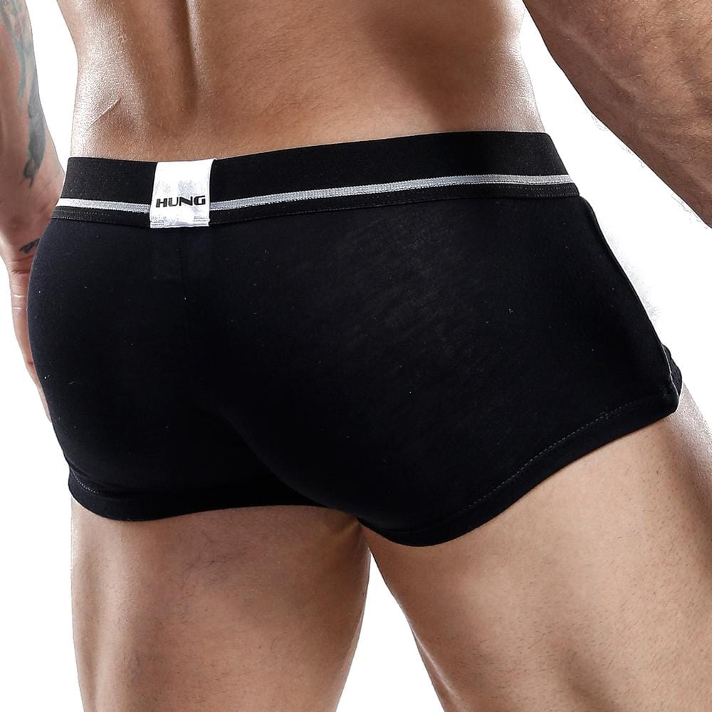 A person is shown from the back wearing Hung Boxer Trunk, featuring a breathable mesh design with a supportive white waistband. The body-hugging fit highlights the lower back and hips, with a label reading HUNG in bold black letters.