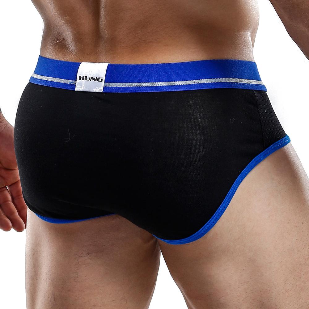 A person wears black and blue Hung Briefs, featuring HUNG branding on the waistband. The image highlights the lower back and waist area, showcasing its breathable mesh fabric for comfort and a functional pouch for support.